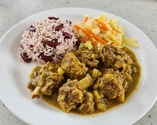 Curried goat with potato, rice and peas and steamed cabbage